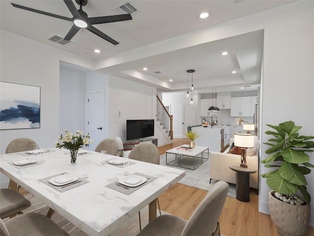 2207 Dan St, Houston, TX 77020 - dining room featuring light wood-style floors, stairs, a ceiling fan, a tray ceiling, and recessed lighting