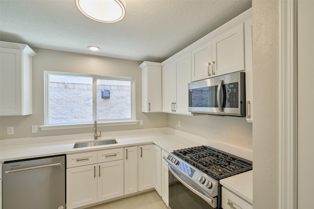 60 Hickory Oak Dr, The Woodlands, TX 77381 - kitchen featuring stainless steel appliances, a sink, a textured ceiling, white cabinets, and light countertops