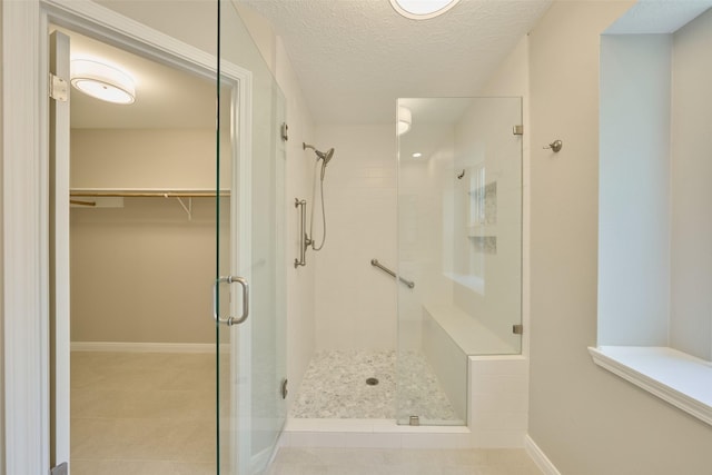 60 Hickory Oak Dr, The Woodlands, TX 77381 - bathroom with a shower stall, a textured ceiling, tile patterned floors, a spacious closet, and baseboards