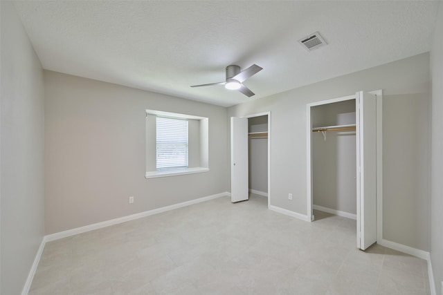 60 Hickory Oak Dr, The Woodlands, TX 77381 - unfurnished bedroom featuring two closets, a ceiling fan, baseboards, and a textured ceiling