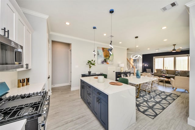 3033 Dennis St, Houston, TX 77004 - kitchen featuring stainless steel appliances, light wood finished floors, white cabinets, ornamental molding, and a ceiling fan