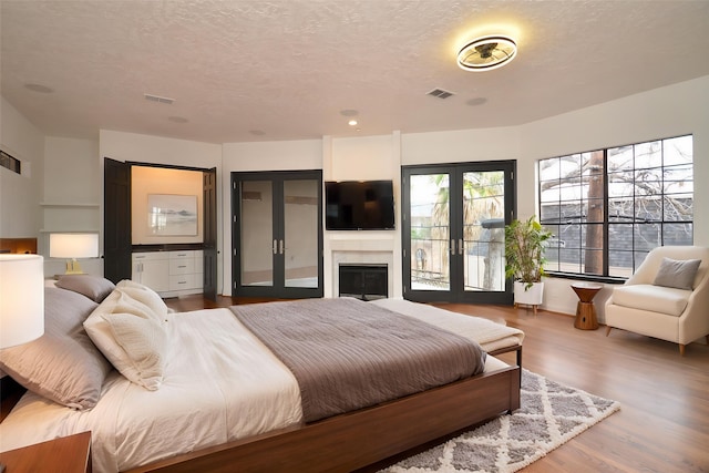 1425 Nantucket Dr Unit D, Houston, TX 77057 - bedroom featuring wood finished floors, french doors, a textured ceiling, access to outside, and a fireplace