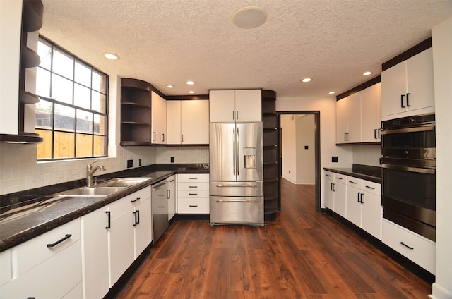1425 Nantucket Dr Unit D, Houston, TX 77057 - kitchen featuring appliances with stainless steel finishes, open shelves, a sink, dark countertops, and a textured ceiling