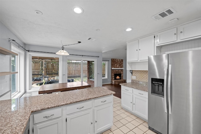 7611 Creekfield Dr, Spring, TX 77379 - kitchen featuring stainless steel fridge, white cabinetry, decorative backsplash, recessed lighting, and light stone counters