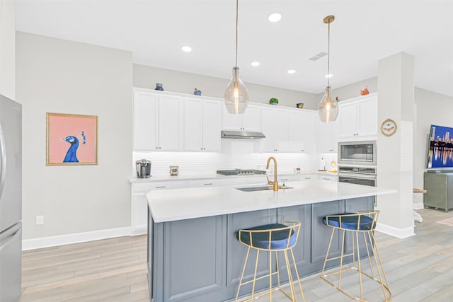 10702 Pleasant View Dr, Missouri City, TX 77459 - kitchen featuring appliances with stainless steel finishes, light wood-style flooring, under cabinet range hood, tasteful backsplash, and recessed lighting