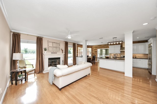 1140 Bartlett Rd, Katy, TX 77493 - living area featuring light wood-style floors, plenty of natural light, ceiling fan, a glass covered fireplace, and crown molding
