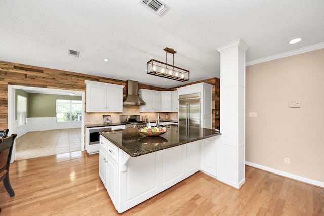 1140 Bartlett Rd, Katy, TX 77493 - kitchen featuring wall chimney exhaust hood, range, built in refrigerator, a peninsula, and light wood-style flooring