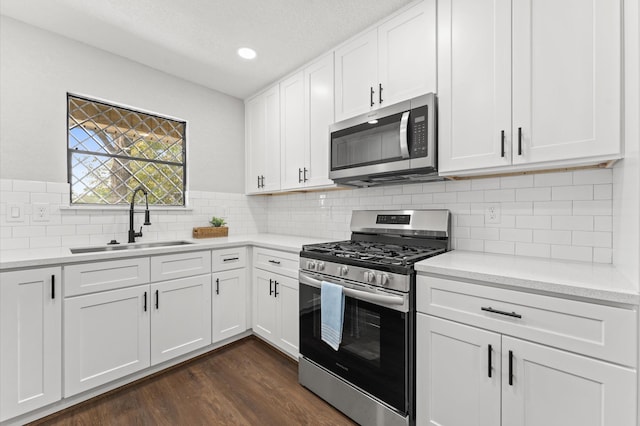 13430 Orleans St, Houston, TX 77015 - kitchen with appliances with stainless steel finishes, a sink, light countertops, dark wood-style floors, and white cabinets