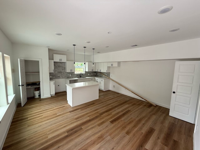 8019 Birmingham St, Houston, TX 77028 - kitchen featuring a center island, white cabinetry, decorative backsplash, wood finished floors, and a sink