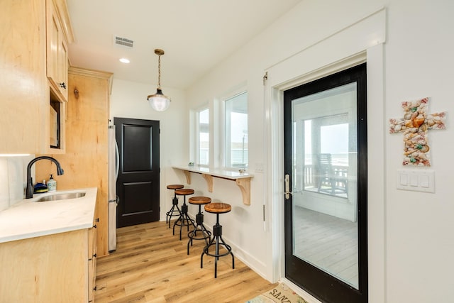 2176 Hwy 87, Gilchrist, TX 77617 - kitchen featuring a sink, freestanding refrigerator, a kitchen bar, light wood-style floors, and light brown cabinets