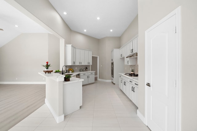 kitchen featuring decorative backsplash, a peninsula, stainless steel appliances, recessed lighting, and light countertops