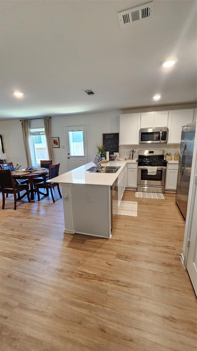 20822 Masella Ridge Dr, New Caney, TX 77357 - kitchen with stainless steel appliances, a peninsula, light wood-style flooring, light countertops, and recessed lighting