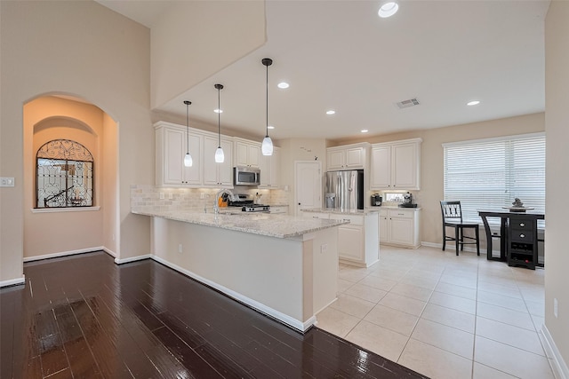 16747 Highland Country Dr, Cypress, TX 77433 - kitchen with appliances with stainless steel finishes, a peninsula, white cabinetry, decorative backsplash, and light stone countertops