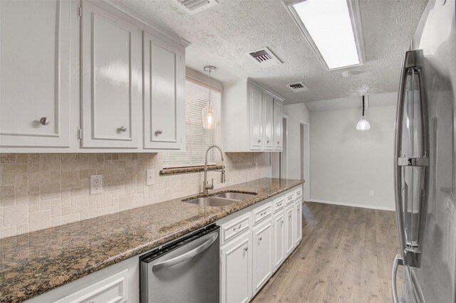 206 Verna St, Jasper, TX 75951 - kitchen with stainless steel appliances, a sink, backsplash, light wood-style flooring, and a textured ceiling