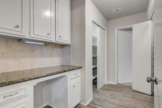 206 Verna St, Jasper, TX 75951 - kitchen with dark stone counters, light wood-type flooring, white cabinets, and a textured ceiling