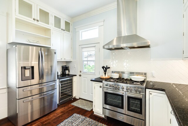 1717 Winnie St, Galveston, TX 77550 - kitchen featuring stainless steel appliances, beverage cooler, wall chimney exhaust hood, ornamental molding, and white cabinetry