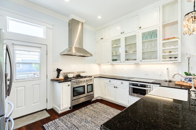 1717 Winnie St, Galveston, TX 77550 - kitchen featuring stainless steel appliances, wall chimney exhaust hood, white cabinetry, dark wood finished floors, and dark stone countertops
