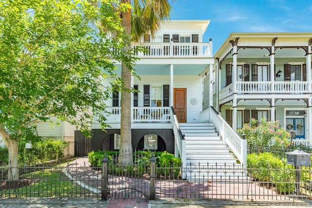 1717 Winnie St, Galveston, TX 77550 - view of front of house with a balcony, a fenced front yard, a porch, and stairs