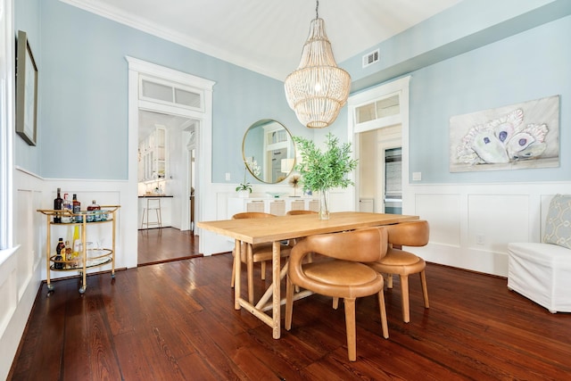 1717 Winnie St, Galveston, TX 77550 - dining space with a decorative wall, a chandelier, wainscoting, dark wood-style flooring, and crown molding