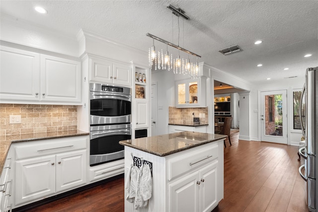 15106 Cranbourne Dr, Houston, TX 77062 - kitchen featuring appliances with stainless steel finishes, a center island, decorative backsplash, dark stone countertops, and white cabinetry