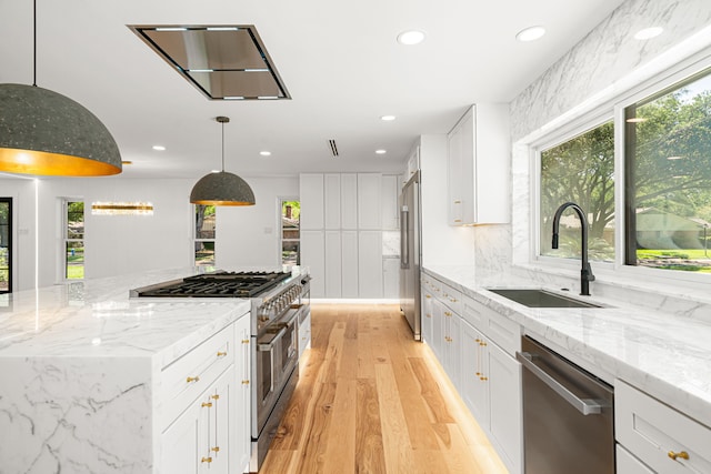 kitchen featuring high end appliances, a sink, light wood finished floors, plenty of natural light, and recessed lighting