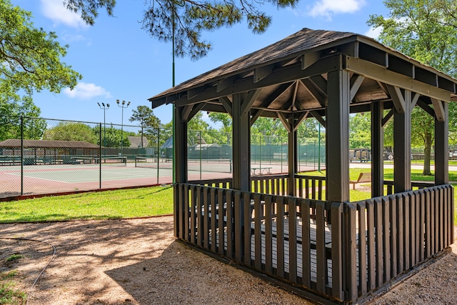 view of community with a tennis court and fence