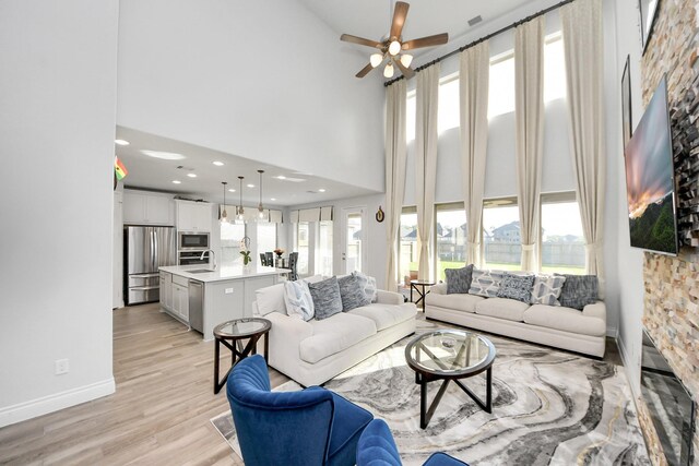1935 Creekwood Cv, Missouri City, TX 77459 - living area with light wood finished floors, a high ceiling, ceiling fan, baseboards, and recessed lighting