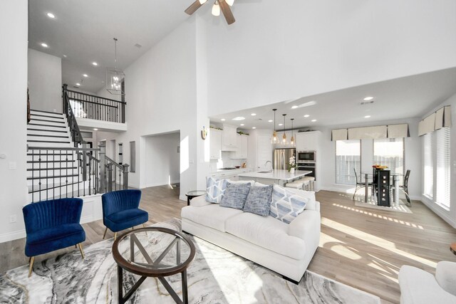 1935 Creekwood Cv, Missouri City, TX 77459 - living area featuring light wood-type flooring, stairway, baseboards, a ceiling fan, and a high ceiling