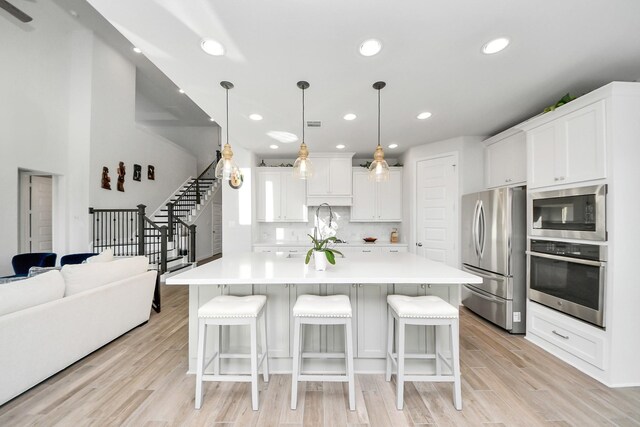 1935 Creekwood Cv, Missouri City, TX 77459 - kitchen with appliances with stainless steel finishes, a breakfast bar area, light wood-style floors, decorative backsplash, and recessed lighting