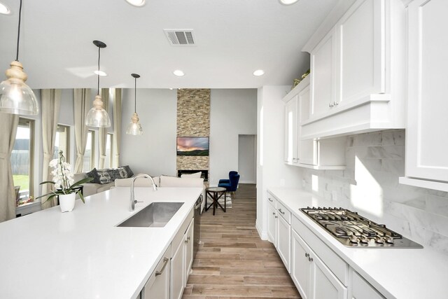 1935 Creekwood Cv, Missouri City, TX 77459 - kitchen with a sink, stainless steel gas cooktop, decorative backsplash, light countertops, and white cabinetry