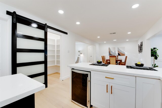 2514 Haverhill Dr, Houston, TX 77008 - kitchen featuring wine cooler, a barn door, light wood-style floors, white cabinetry, and light countertops