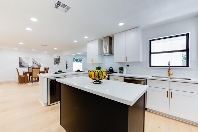 2514 Haverhill Dr, Houston, TX 77008 - kitchen with wall chimney range hood, a sink, beverage cooler, a center island, and light wood-style flooring