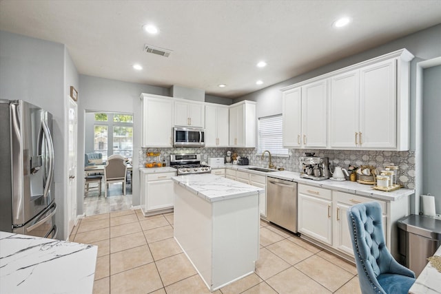 5206 Spring Oak Dr, Pasadena, TX 77505 - kitchen with stainless steel appliances, a sink, decorative backsplash, a kitchen island, and white cabinetry
