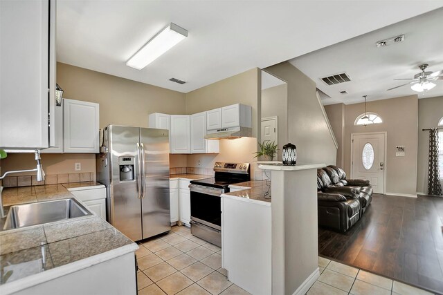 34606 Lake Side Dr, Brookshire, TX 77423 - kitchen with stainless steel appliances, tile counters, a sink, under cabinet range hood, and white cabinets