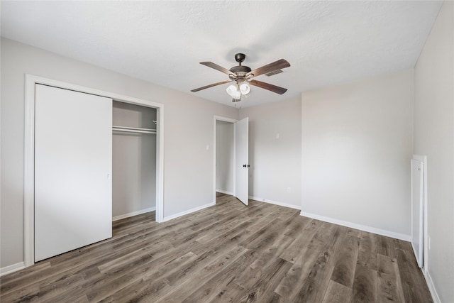 unfurnished bedroom featuring wood finished floors, a closet, baseboards, and ceiling fan