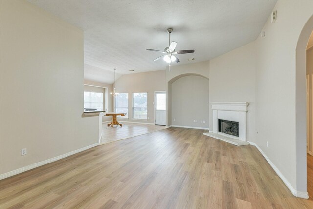 2212 Highland Crossing Dr, Conroe, TX 77304 - unfurnished living room with arched walkways, lofted ceiling, light wood finished floors, a ceiling fan, and baseboards