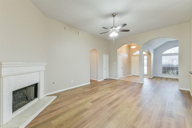 2212 Highland Crossing Dr, Conroe, TX 77304 - unfurnished living room featuring ceiling fan, a high end fireplace, light wood-type flooring, and arched walkways