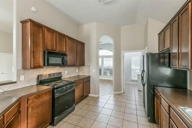 2212 Highland Crossing Dr, Conroe, TX 77304 - kitchen featuring black appliances, dark countertops, backsplash, arched walkways, and lofted ceiling
