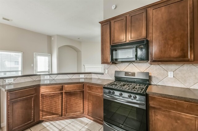 2212 Highland Crossing Dr, Conroe, TX 77304 - kitchen featuring black microwave, gas range, dark countertops, and a peninsula
