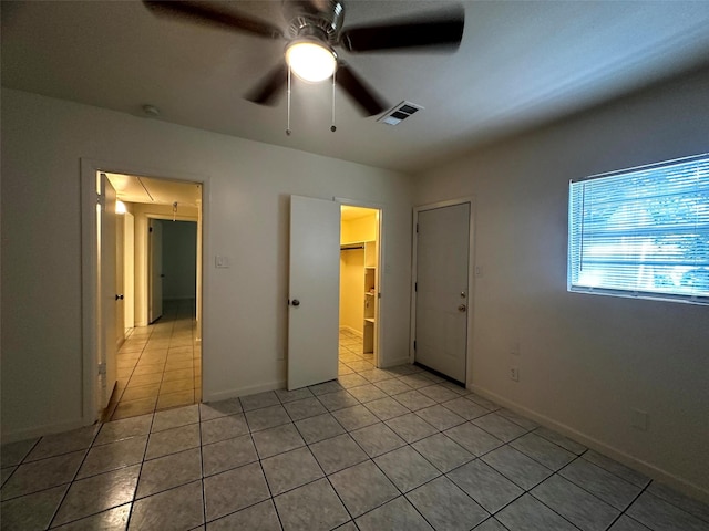 1023 W Snyder St, Alvin, TX 77511 - unfurnished bedroom with light tile patterned floors, baseboards, a ceiling fan, and a walk in closet