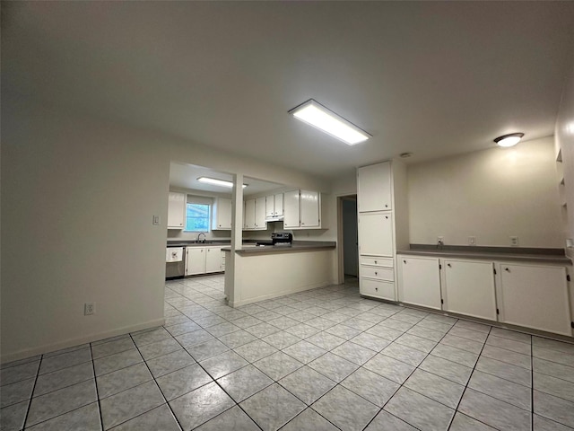 1023 W Snyder St, Alvin, TX 77511 - kitchen featuring light tile patterned floors, stainless steel dishwasher, under cabinet range hood, a peninsula, and dark countertops