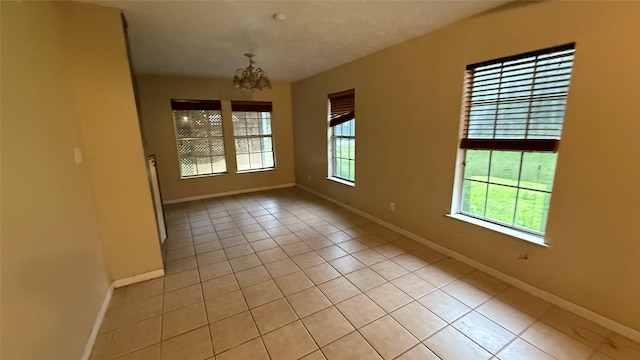 530 N Cattle Dr, Onalaska, TX 77360 - empty room featuring plenty of natural light, light tile patterned flooring, a chandelier, and baseboards