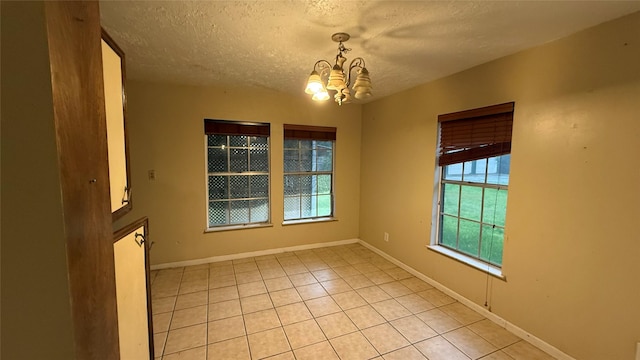 530 N Cattle Dr, Onalaska, TX 77360 - empty room featuring a chandelier, a textured ceiling, light tile patterned floors, and baseboards