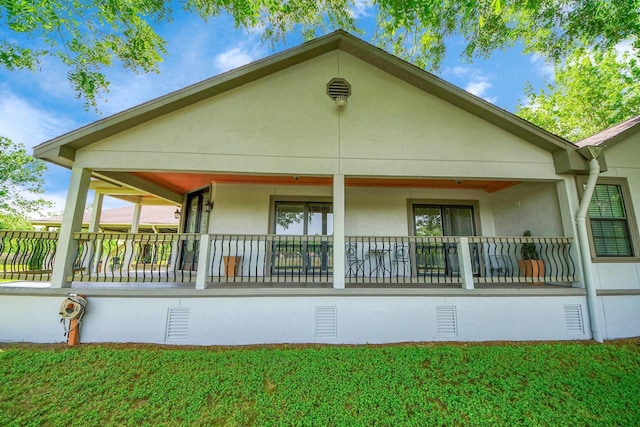 9731 Hadden Rd, Baytown, TX 77521 - rear view of house with stucco siding, covered porch, and a yard