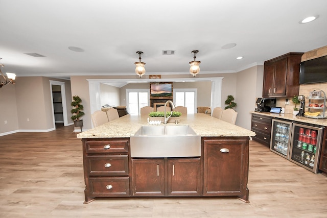 9731 Hadden Rd, Baytown, TX 77521 - kitchen featuring a sink, hanging light fixtures, light wood-style flooring, light stone counters, and tasteful backsplash