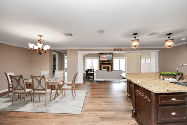 9731 Hadden Rd, Baytown, TX 77521 - dining area with ornamental molding, light wood finished floors, baseboards, and a chandelier