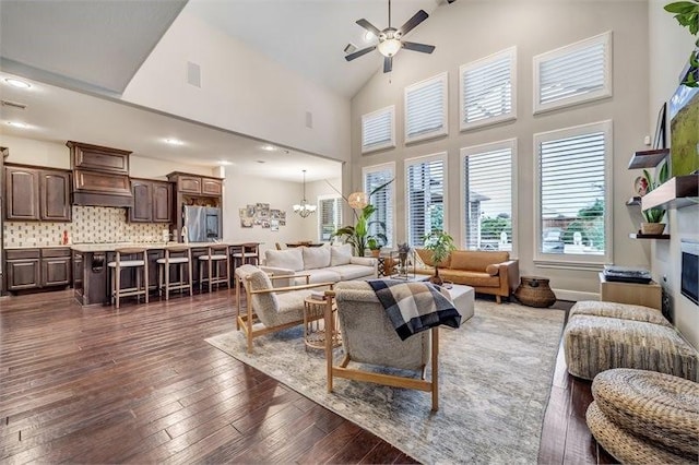10210 Grape Creek Grove Ln, Cypress, TX 77433 - living area featuring a ceiling fan, a glass covered fireplace, dark wood-style flooring, high vaulted ceiling, and a chandelier