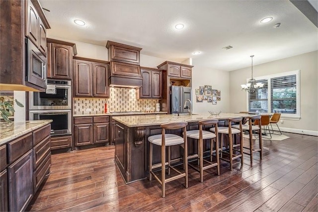 10210 Grape Creek Grove Ln, Cypress, TX 77433 - kitchen featuring stainless steel appliances, a breakfast bar area, dark wood finished floors, dark brown cabinetry, and recessed lighting