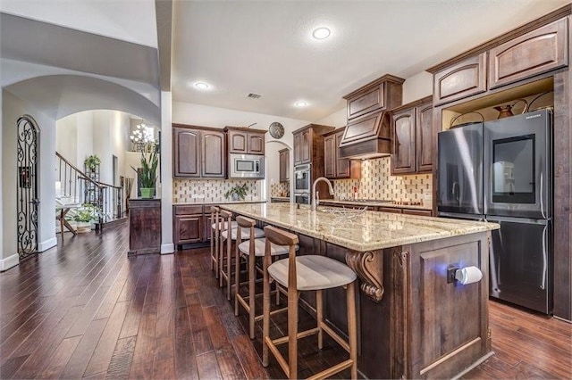 10210 Grape Creek Grove Ln, Cypress, TX 77433 - kitchen with appliances with stainless steel finishes, arched walkways, dark wood-type flooring, light stone countertops, and recessed lighting