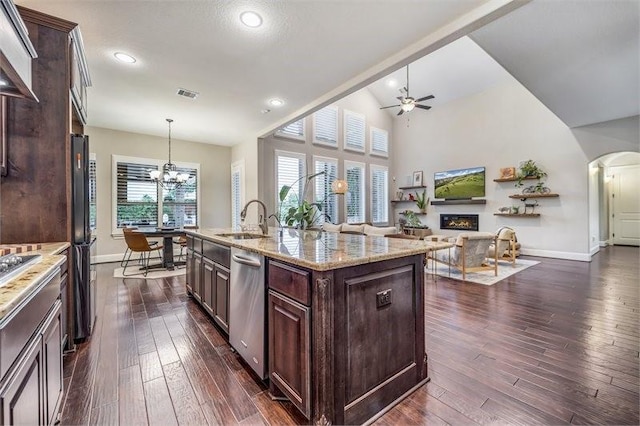 10210 Grape Creek Grove Ln, Cypress, TX 77433 - kitchen featuring stainless steel dishwasher, a sink, baseboards, arched walkways, and dark brown cabinetry